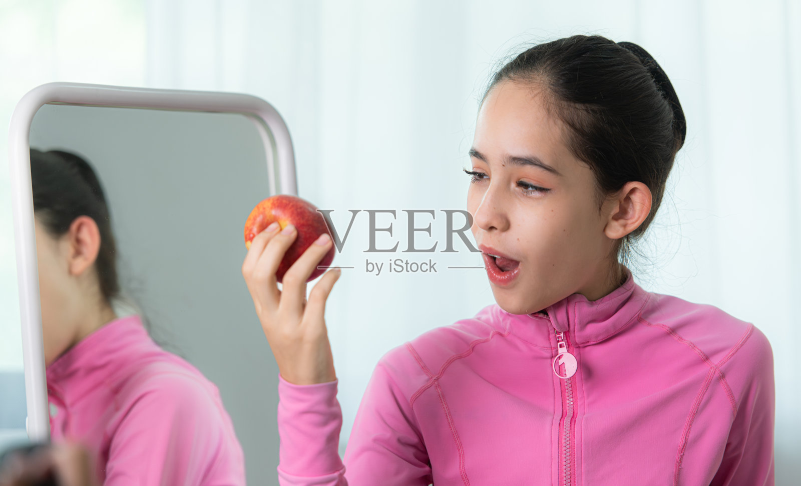 一位身穿粉色运动服的芭蕾舞女学生在练习芭蕾舞前吃了一个苹果照片摄影图片