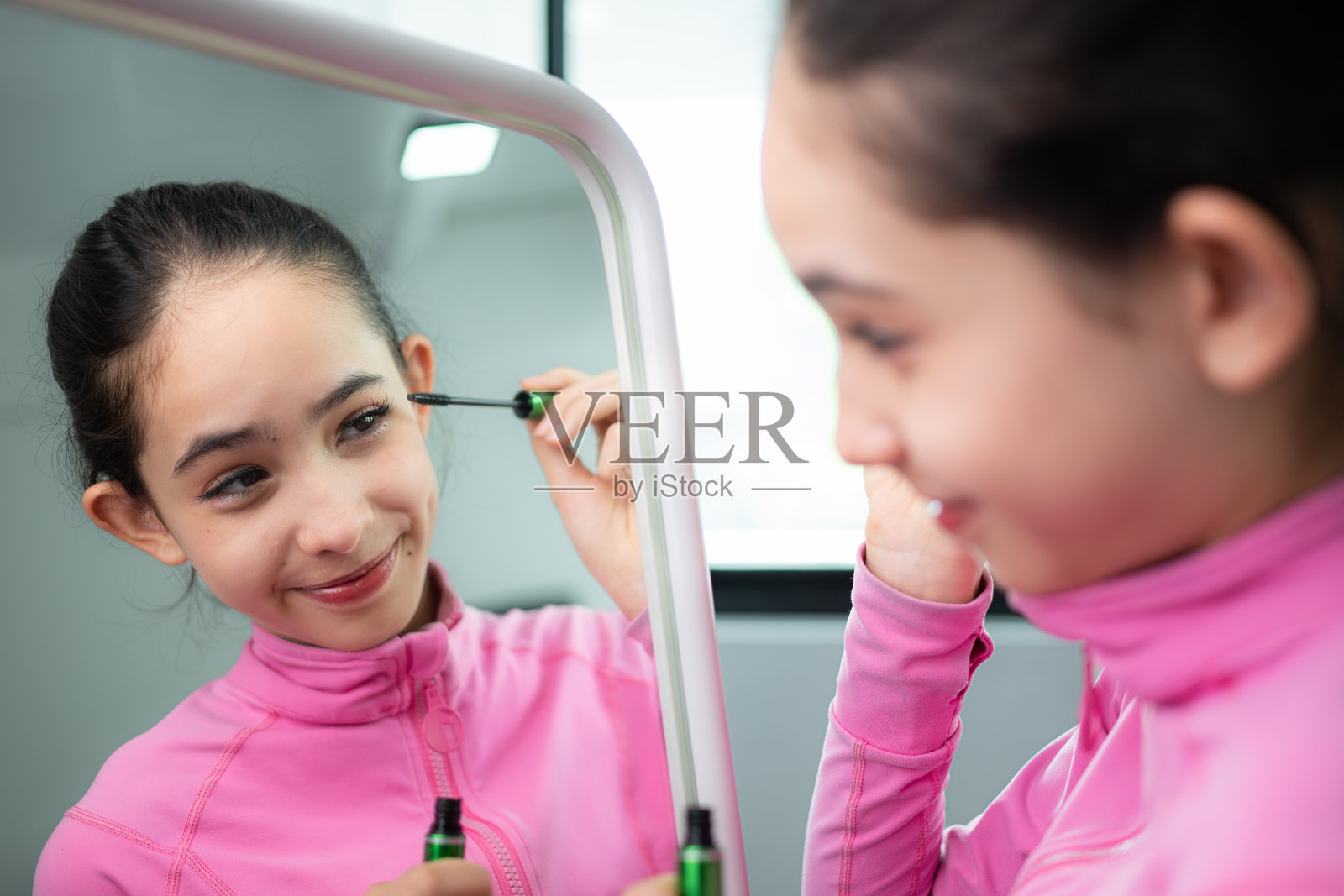 一名身穿粉色运动服的芭蕾舞女学生在表演芭蕾舞前用睫毛膏涂睫毛并化妆照片摄影图片