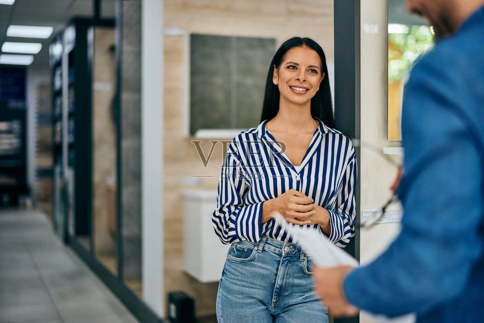 一位微笑的女顾客正和一位男售货员交谈,准备为她的家买些家具。照片摄影图片