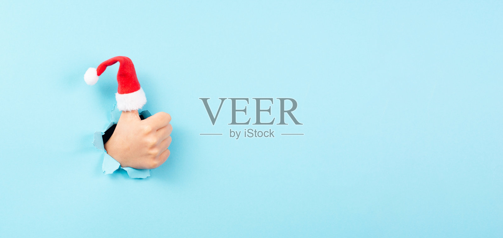 竖起大拇指,圣诞老人的帽子,圣诞假期,积极的手势,乐观和情感,冬天照片摄影图片