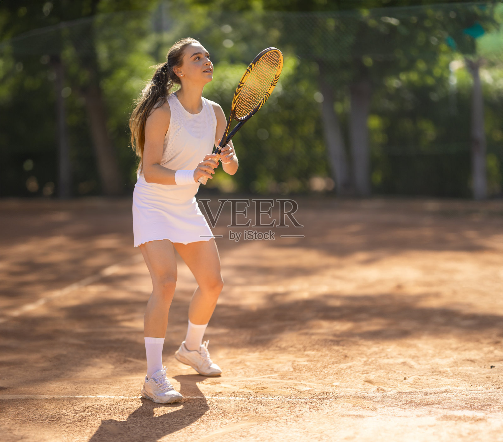 一个女人正在红土场上打网球照片摄影图片