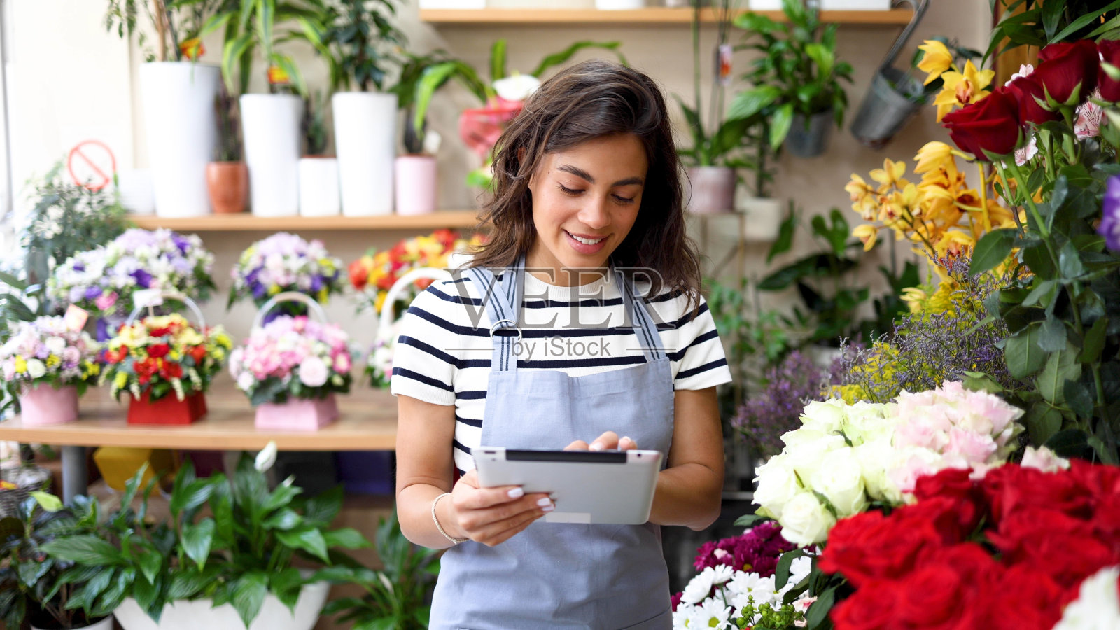 微笑的花商一边享受一边经营她的生意照片摄影图片