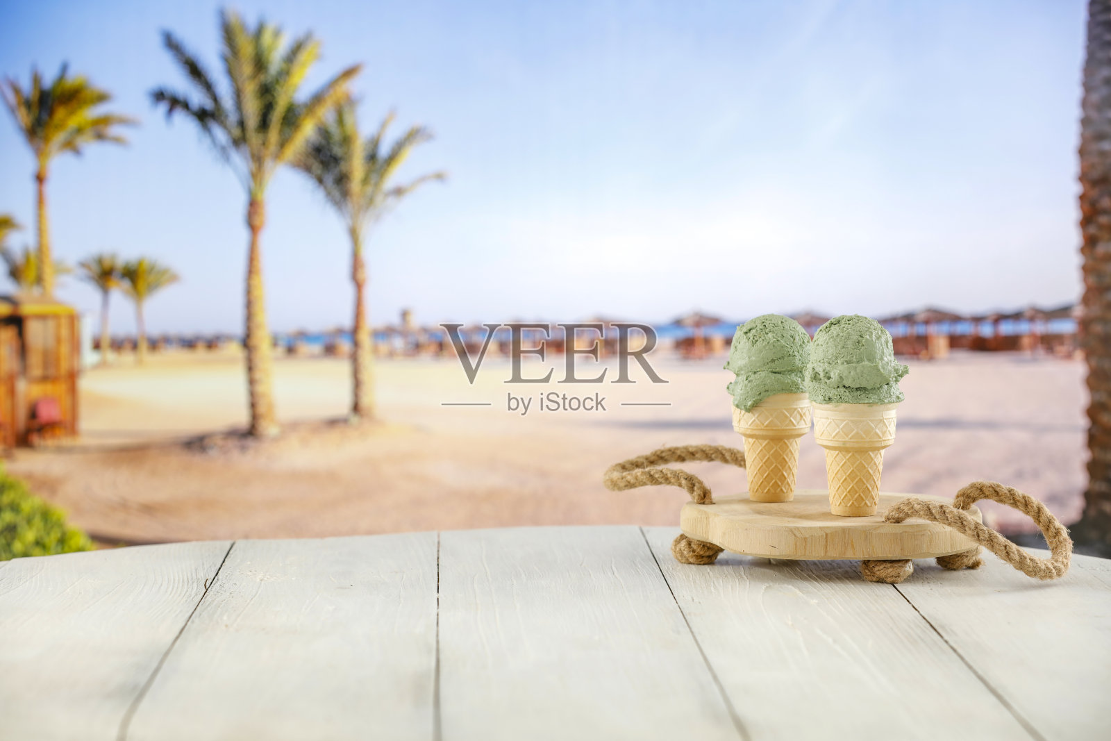 这张特写是在模糊的热带海滩背景下,桌子上的华夫蛋筒冰淇淋。照片摄影图片