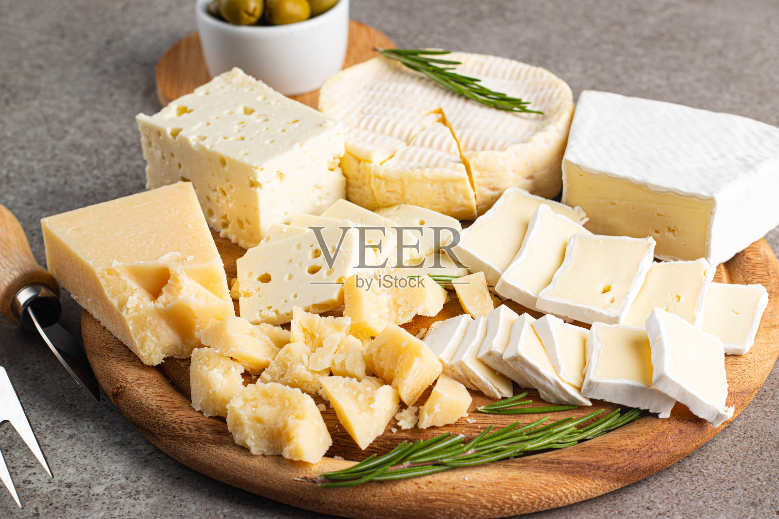 木板上有各种奶酪和橄榄。布里干酪。乳酪。帕尔马干酪,菲达干酪,蓝纹奶酪。意大利奶酪,法国奶酪。照片摄影图片