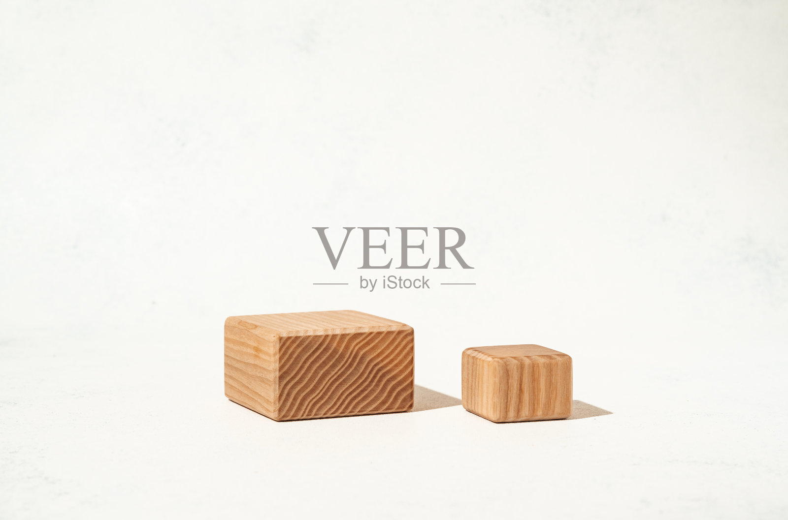 一个展示美妆产品的模拟场景,在白色背景上有纹理的木制立方体基座。摄影工作室。照片摄影图片