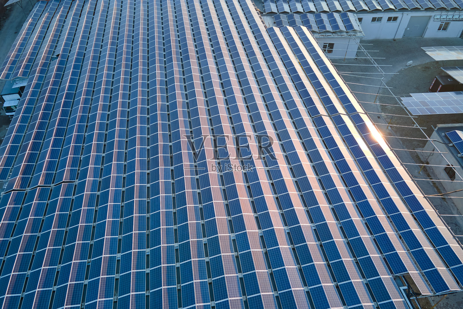 鸟瞰安装在工业建筑屋顶上的蓝色光伏太阳能板,产生绿色生态电力。生产可持续能源的理念照片摄影图片