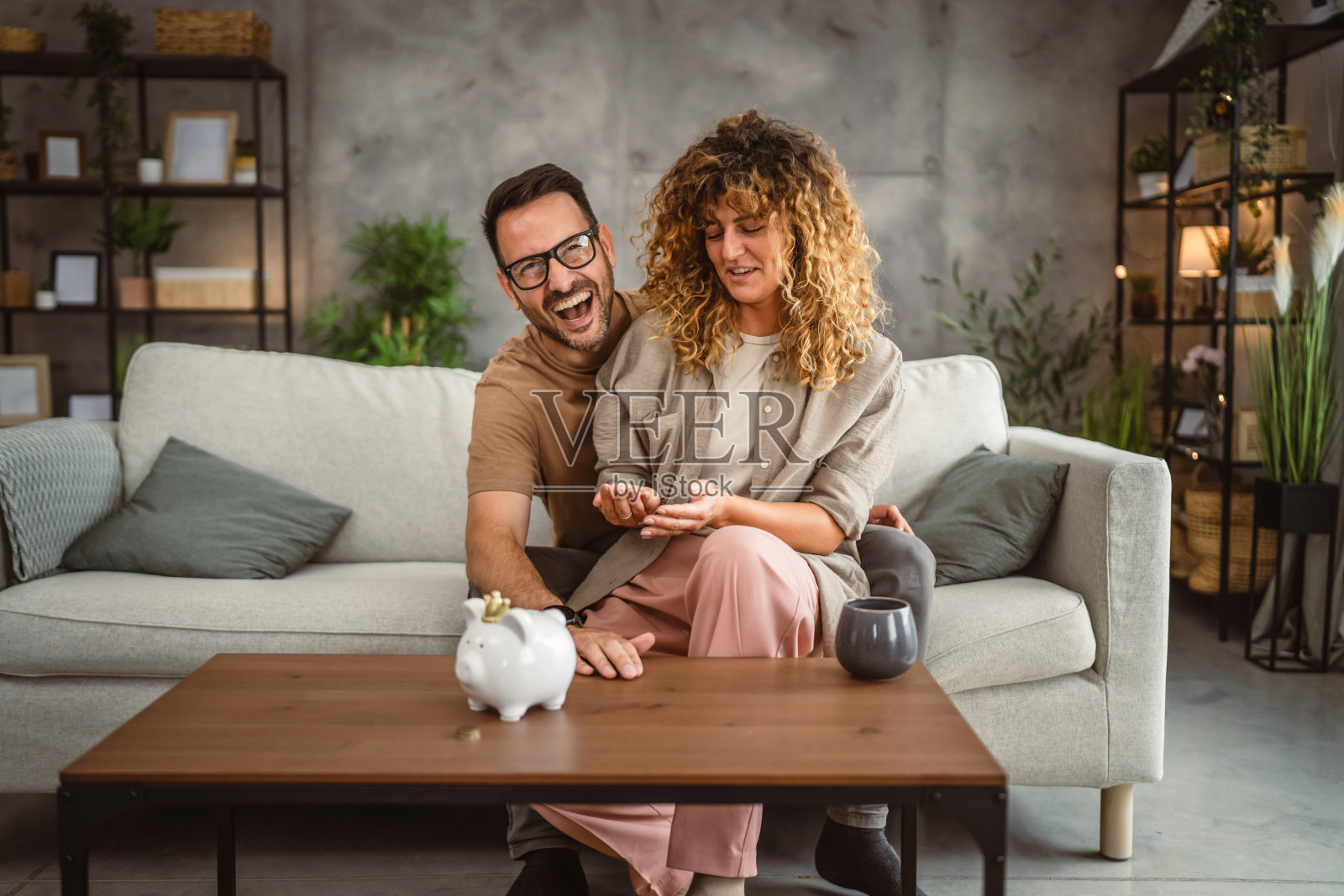 成年夫妇妻子和丈夫一起把钱存到存钱罐里照片摄影图片