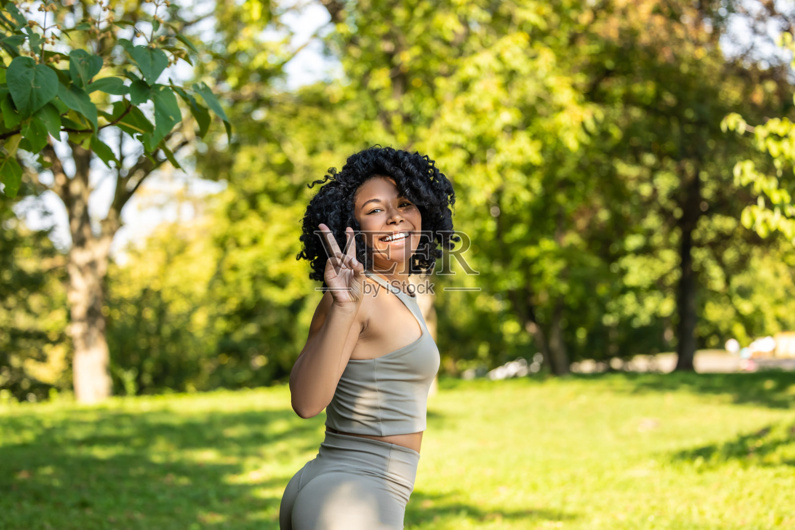 漂亮的卷发女人在公园里健身,看起来很开心照片摄影图片
