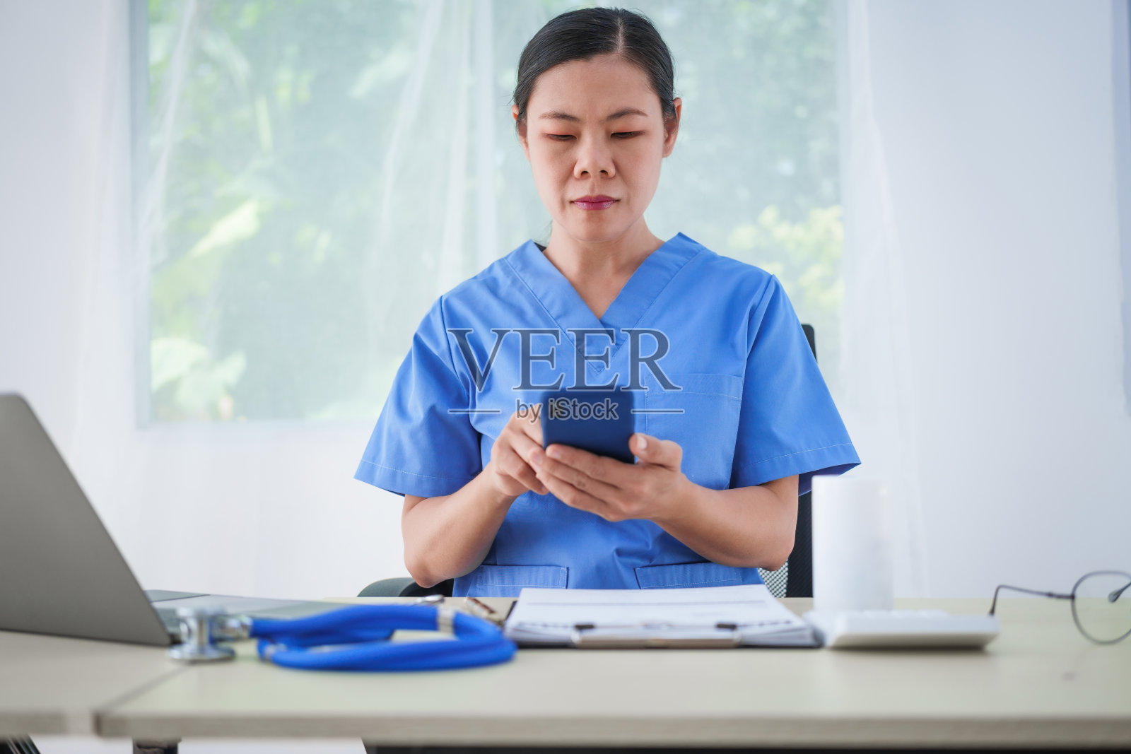 一名亚洲女护士坐在桌子旁,在网上咨询期间与病人通话,解释药物。这种更快、更便宜的方法有助于预防疾病的传播和缓解照片摄影图片