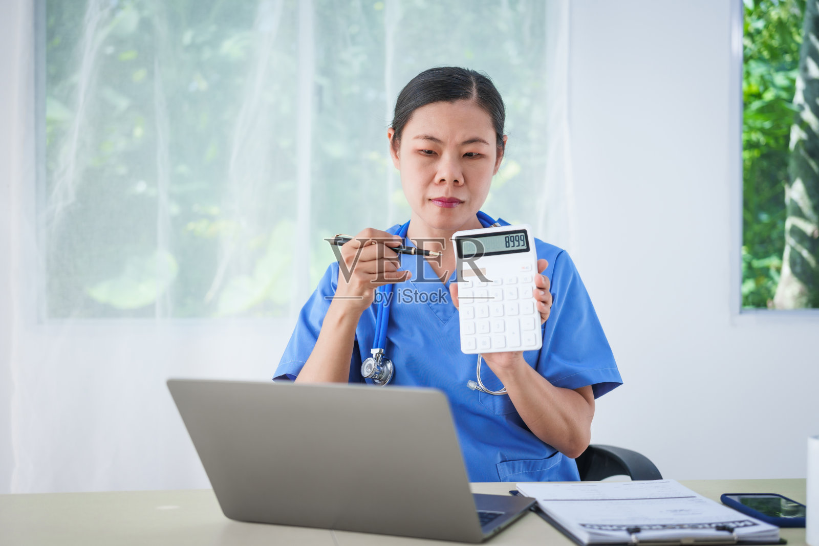 一名亚洲女护士坐在桌子旁,在网上咨询期间与病人通话,解释药物。这种更快、更便宜的方法有助于预防疾病的传播和缓解照片摄影图片