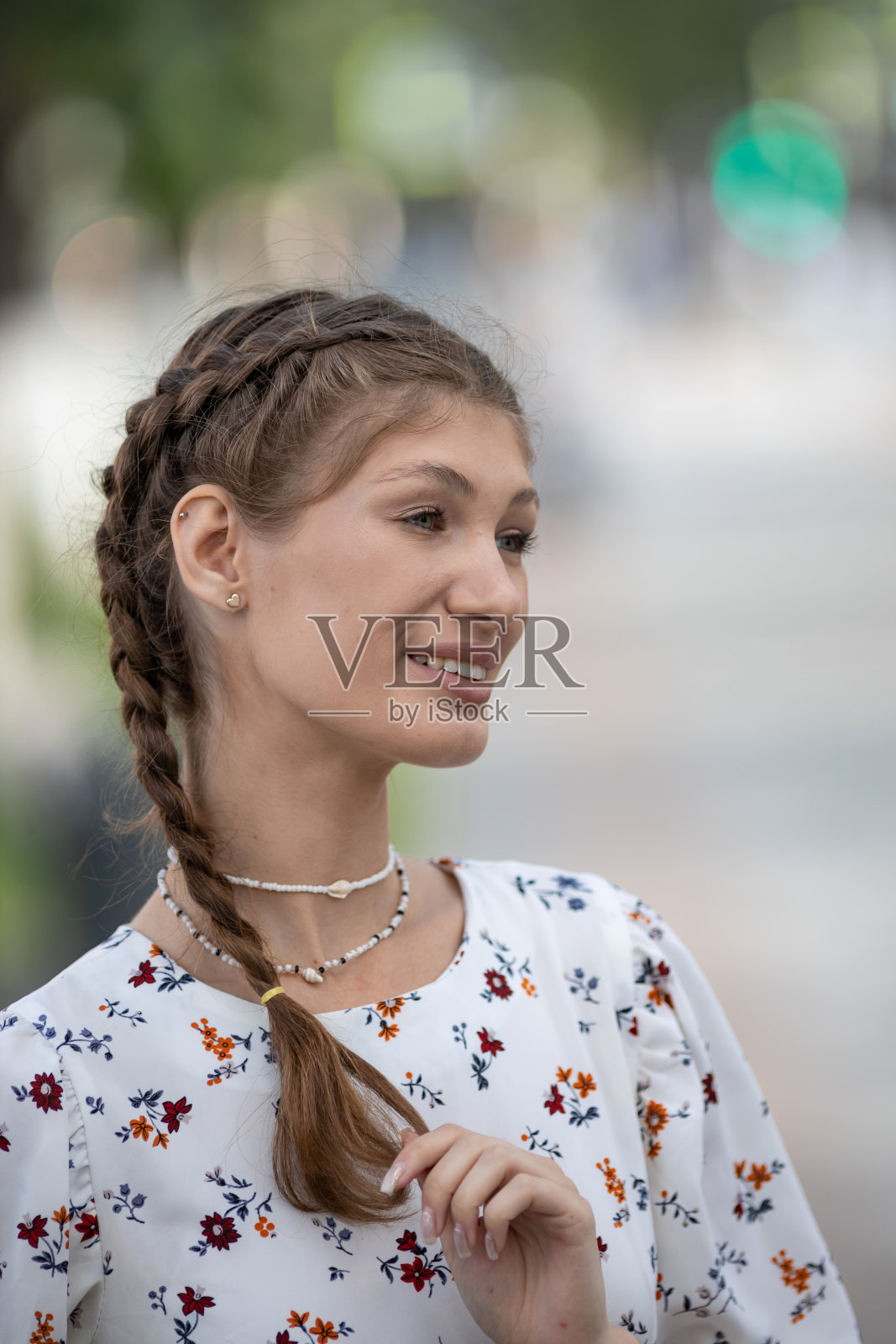 快乐的年轻漂亮的女人握着她长长的辫子,对健康闪亮的头发感到满意。美丽的肖像微笑的女孩与时尚的辫子。护发护理产品。照片摄影图片