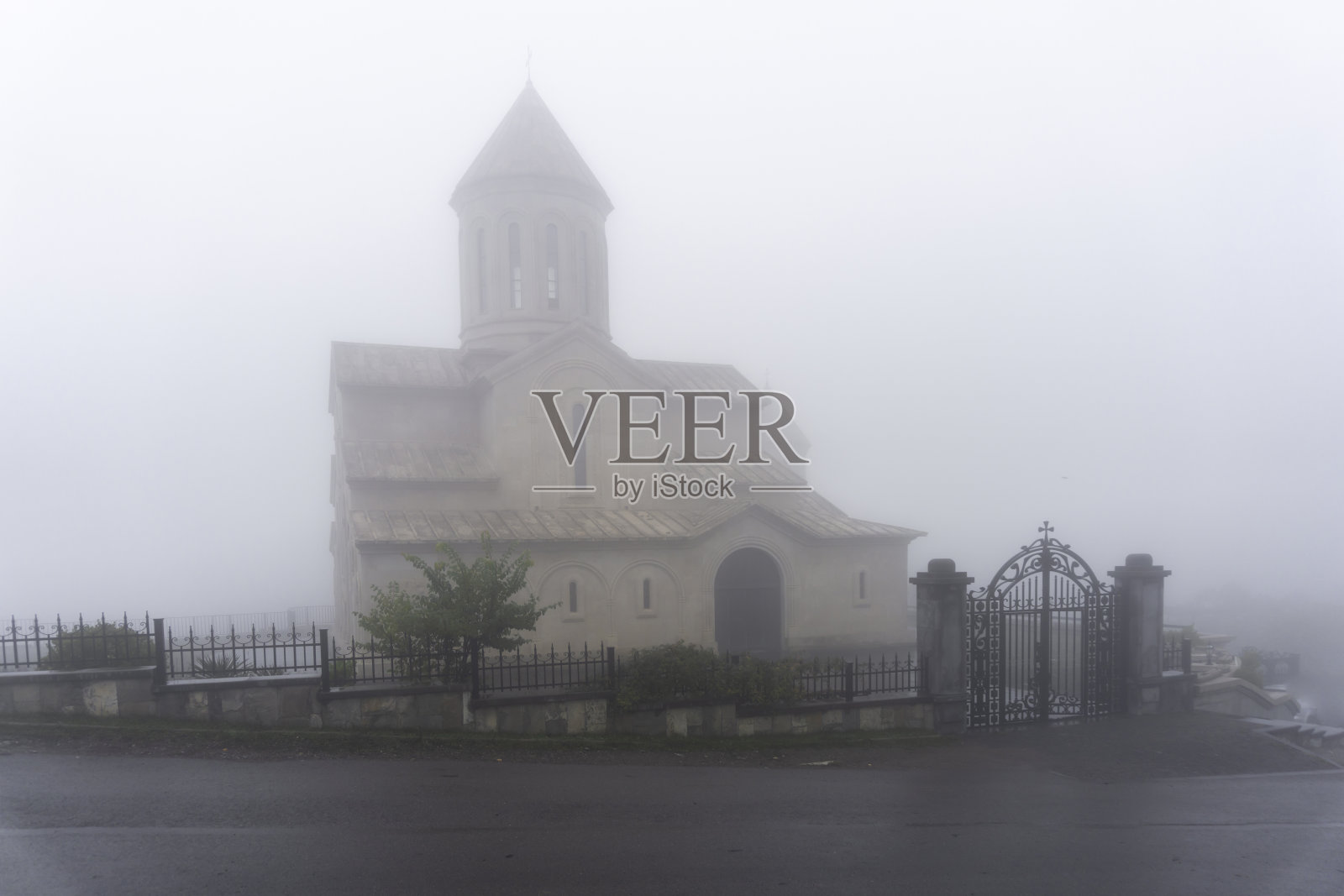 教堂的正面部分隐藏在雾中,有一道漂亮的锻铁栅栏和一扇门照片摄影图片