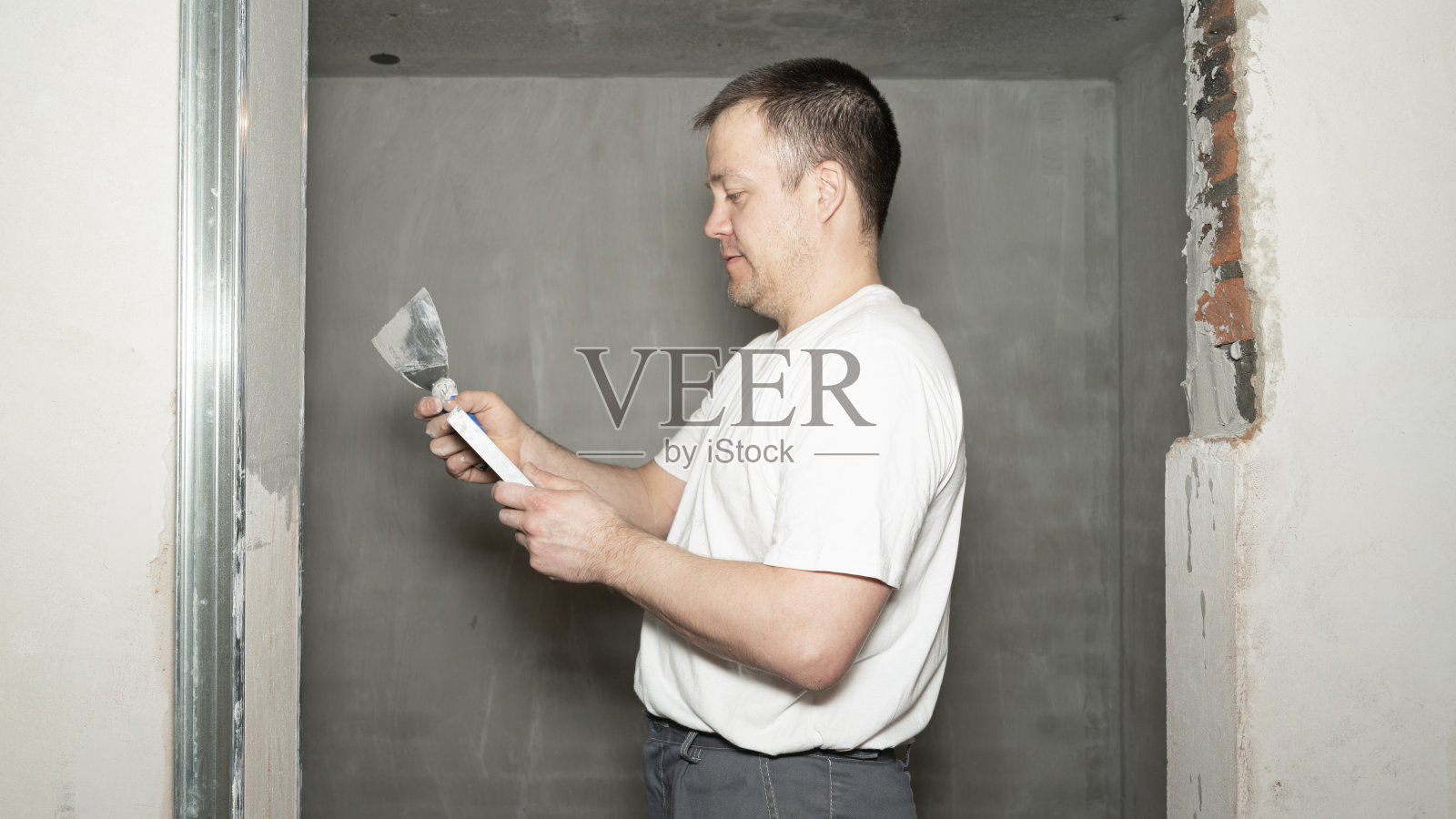 工人正在用抹刀在墙上抹石膏。照片摄影图片