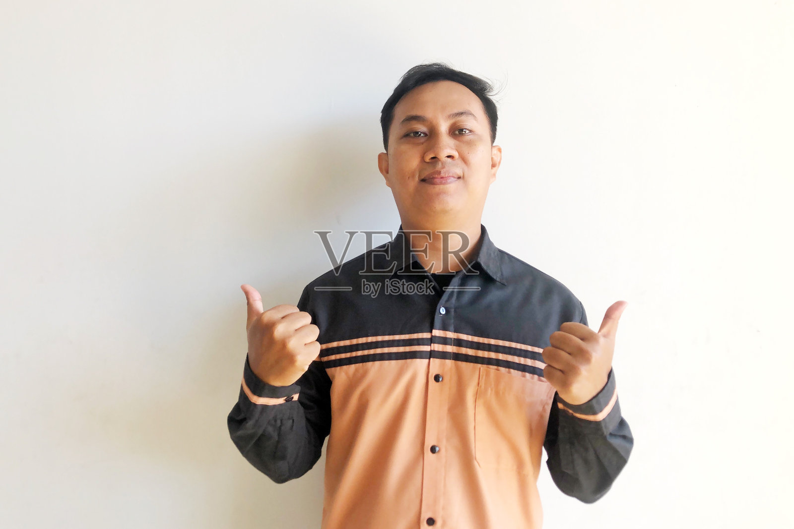 一名亚洲男子对着镜头开心地笑着,竖起大拇指照片摄影图片