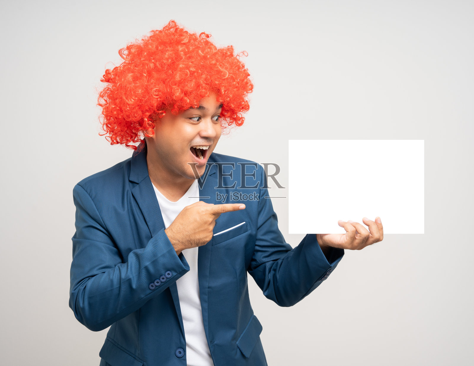 留着非洲式发型的年轻亚洲男子手持白板做文字广告。在孤立的白色背景上穿着西装外套,微笑着的快乐男人。照片摄影图片