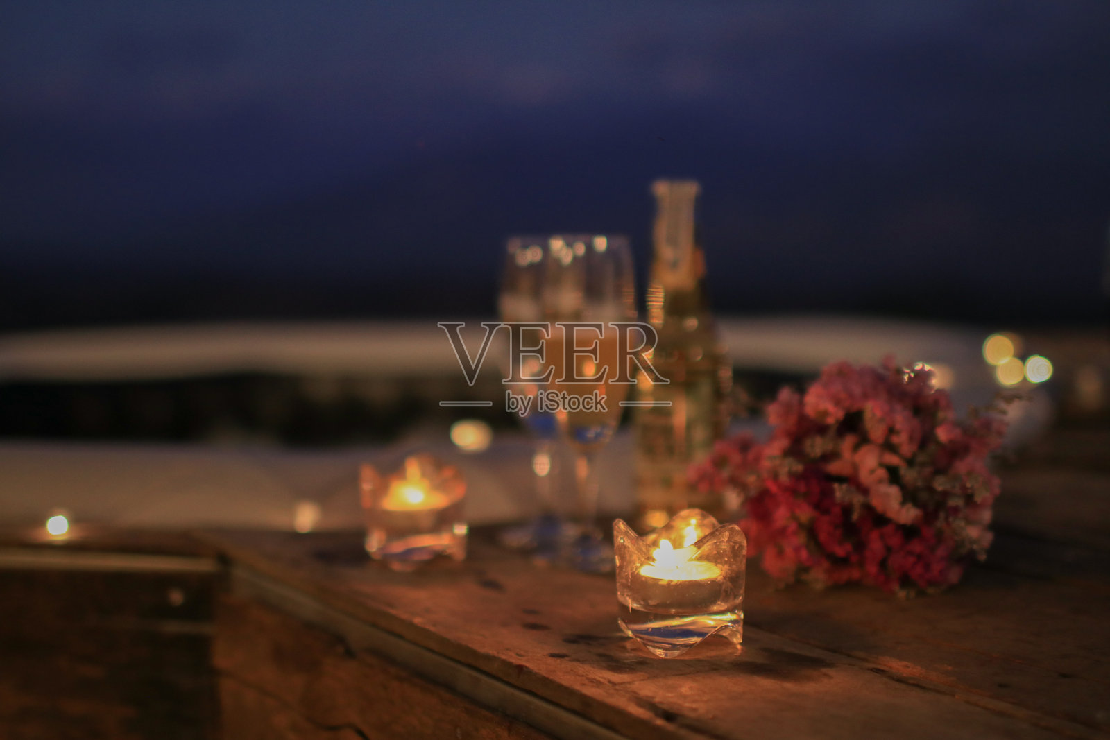 一杯香槟,蜡烛和鲜花,在夜空下的室外热水浴缸里浪漫约会。约会的概念。照片摄影图片