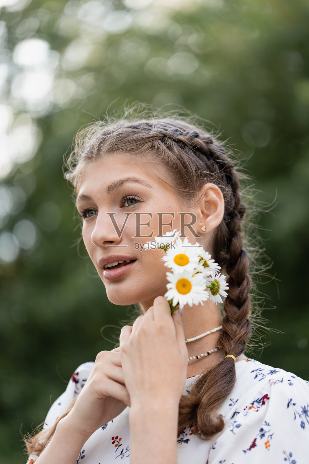 在一个炎热的夏日,年轻的女孩穿着浅色的连衣裙,手里拿着雏菊照片摄影图片