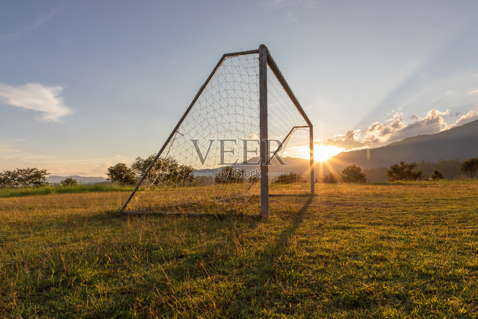 足球场上的乡村山峦落日的背景。照片摄影图片