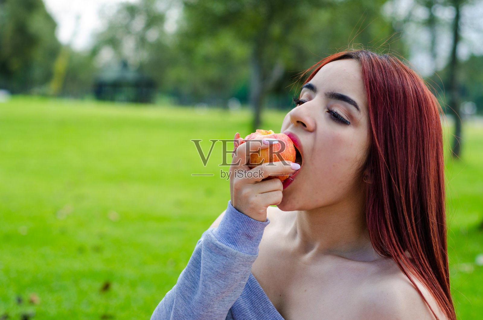 性感的年轻女子在公园里吃健康的食物照片摄影图片