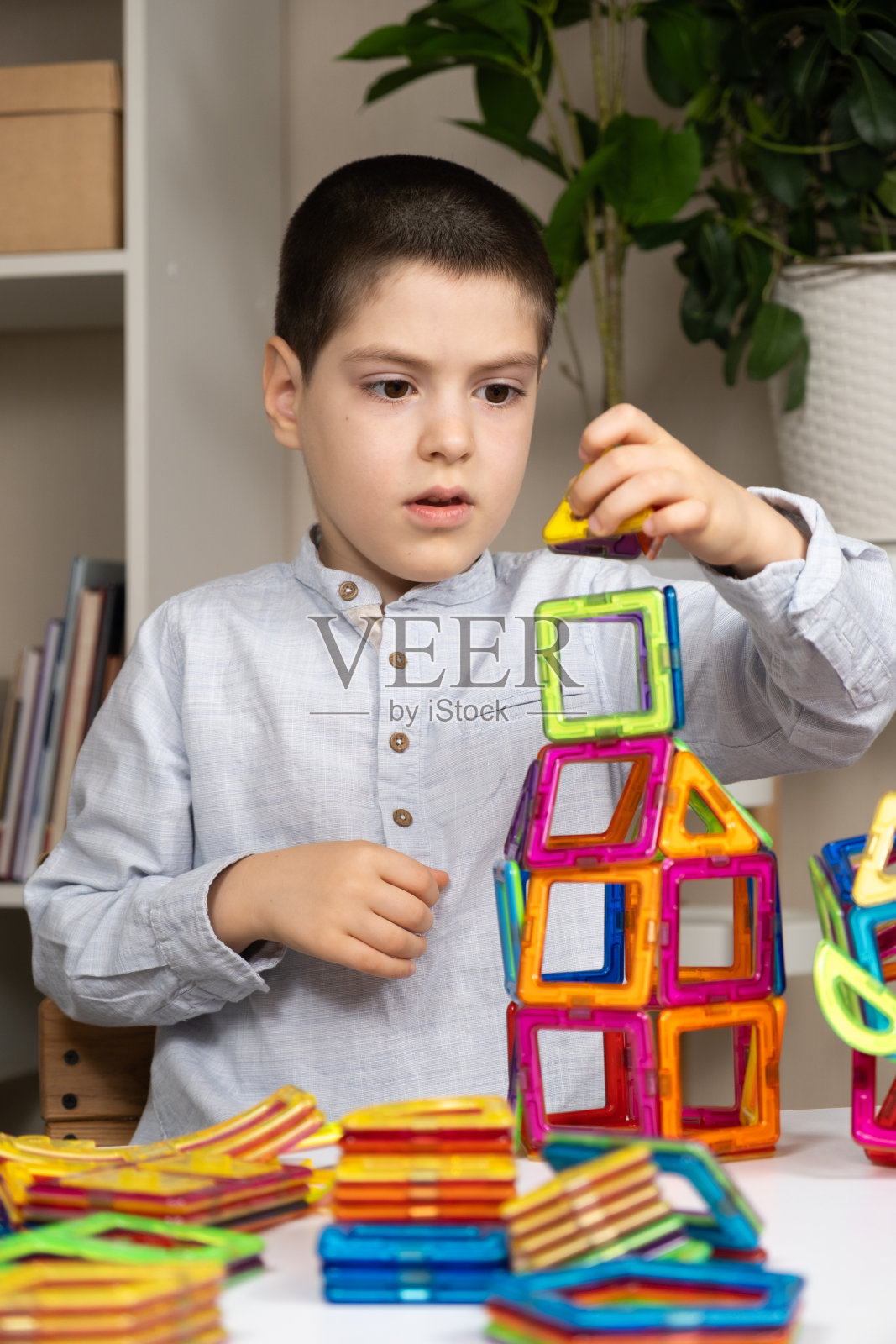 一个六岁的小男孩在玩一个磁性建筑装置。为孩子们开发想象力的玩具。照片摄影图片
