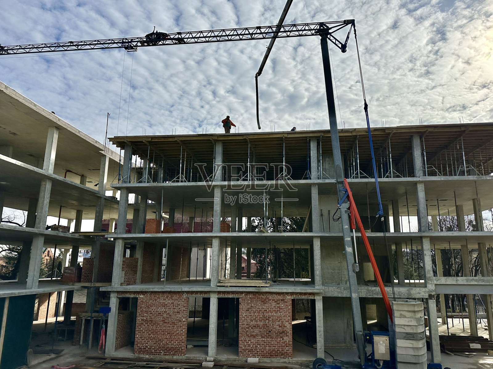 建筑工地上的工人们在一座高层建筑的背景下施工。建筑工人在装配起重机的背景下工作。利沃夫,圣梅尔尼克,2024年2月20日照片摄影图片