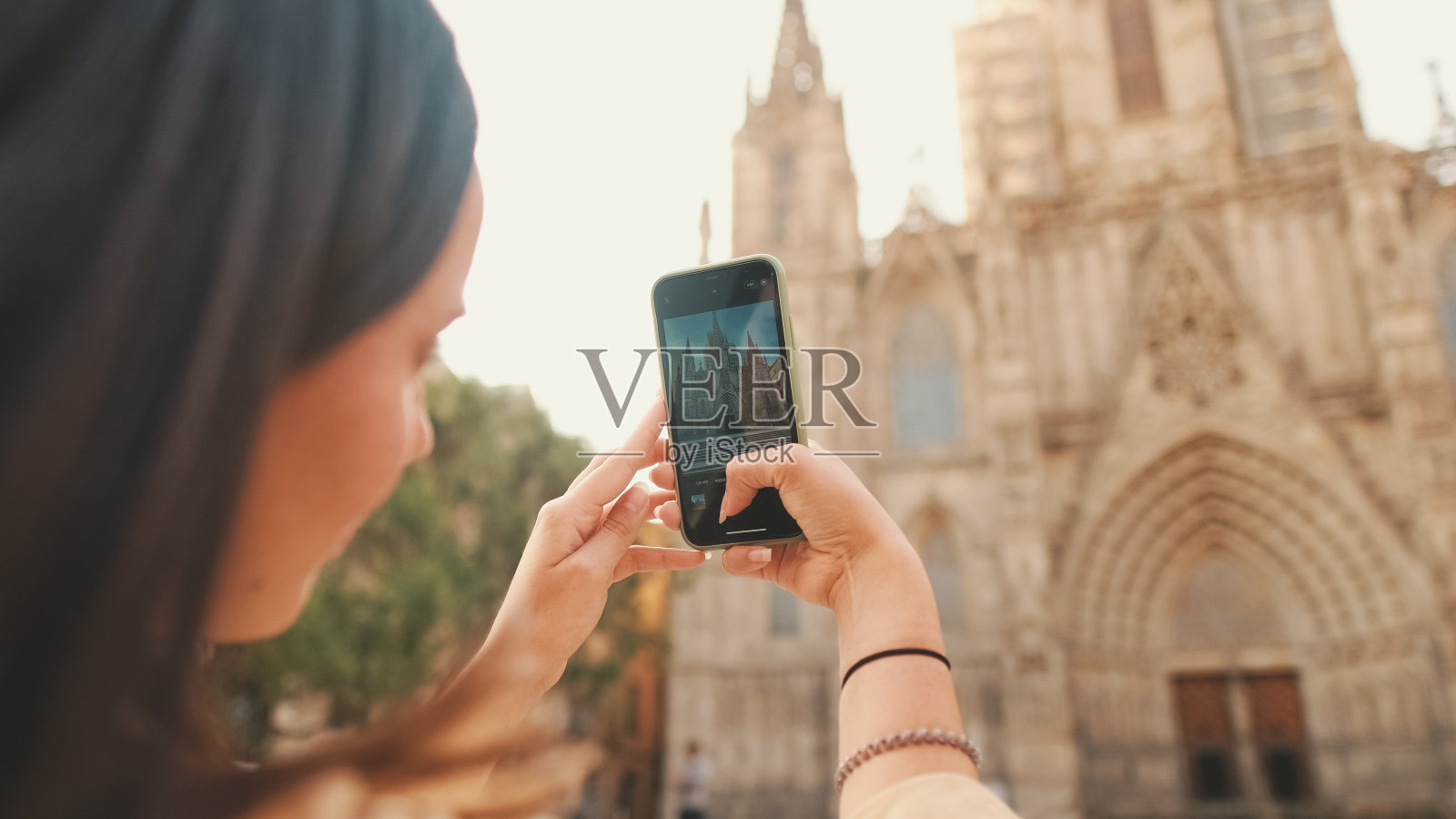 旅行者女孩背着背包,用手机拍下了欧洲城市历史地段的一座老建筑的背影照片摄影图片