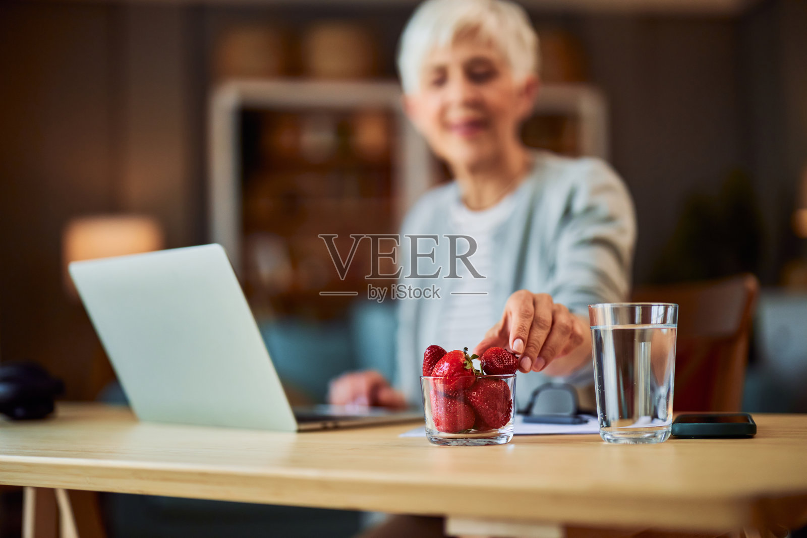 一位年长的成年妇女在工作间隙吃健康的零食照片摄影图片