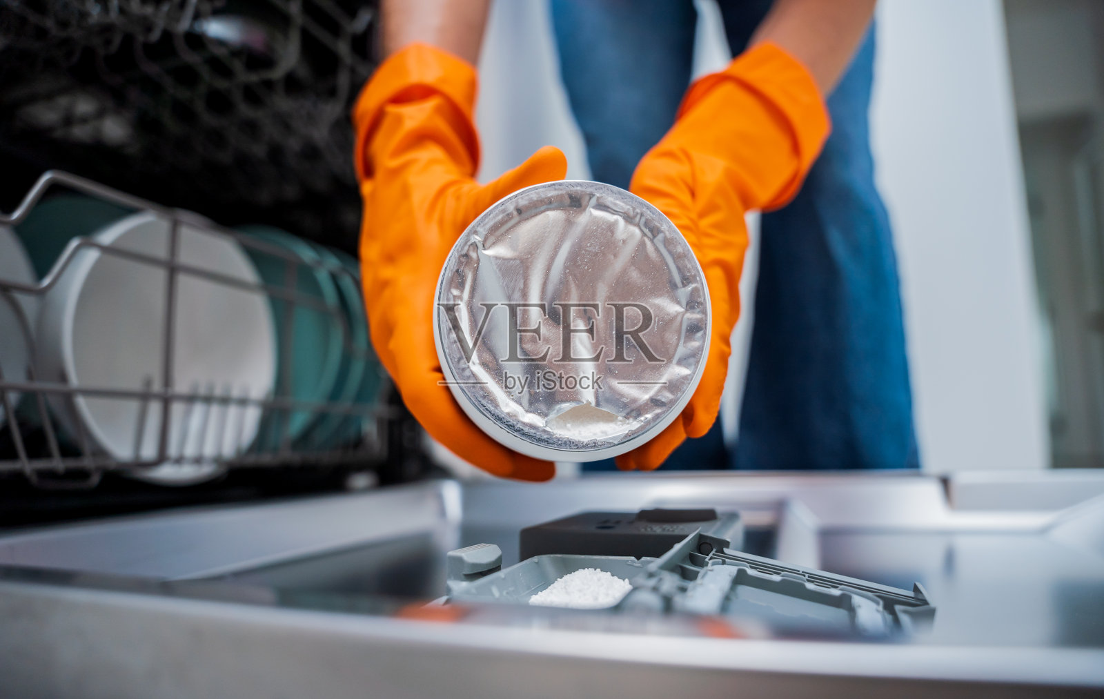 女人往洗碗机的抽屉里加洗涤剂照片摄影图片