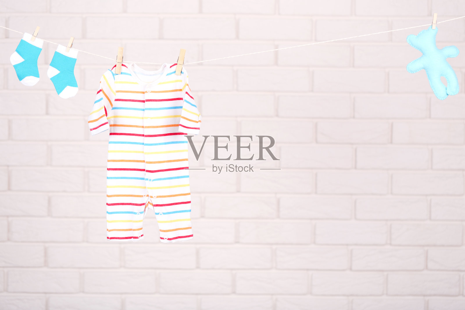 宝宝的衣服和软玩具挂在砖墙背景照片摄影图片