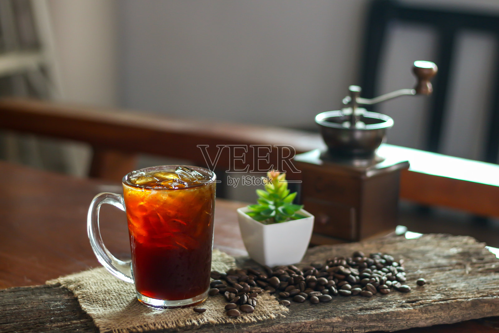 把美式冰咖啡放在旧木器和咖啡豆上,研磨咖啡。照片摄影图片