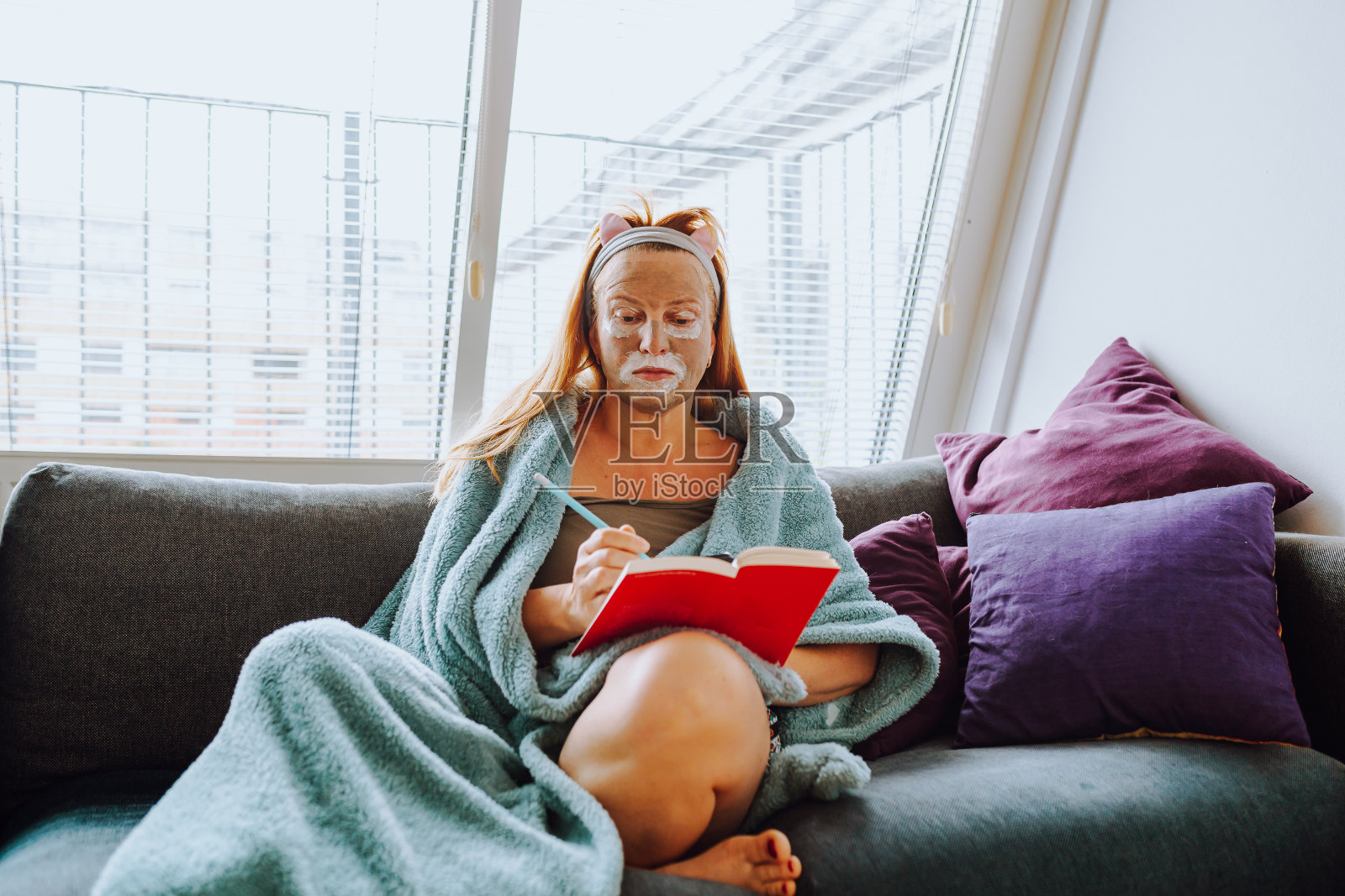 中年妇女在家里的沙发上戴着化妆面具照片摄影图片