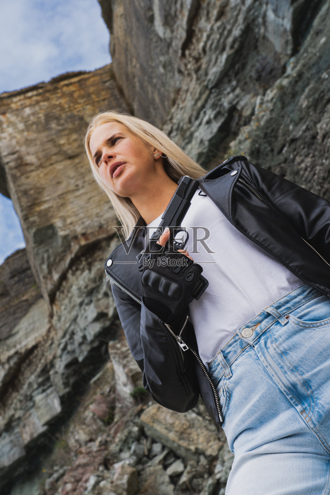 美国经典手枪M1911在一个金发女孩的手在户外。垂直的照片。照片摄影图片