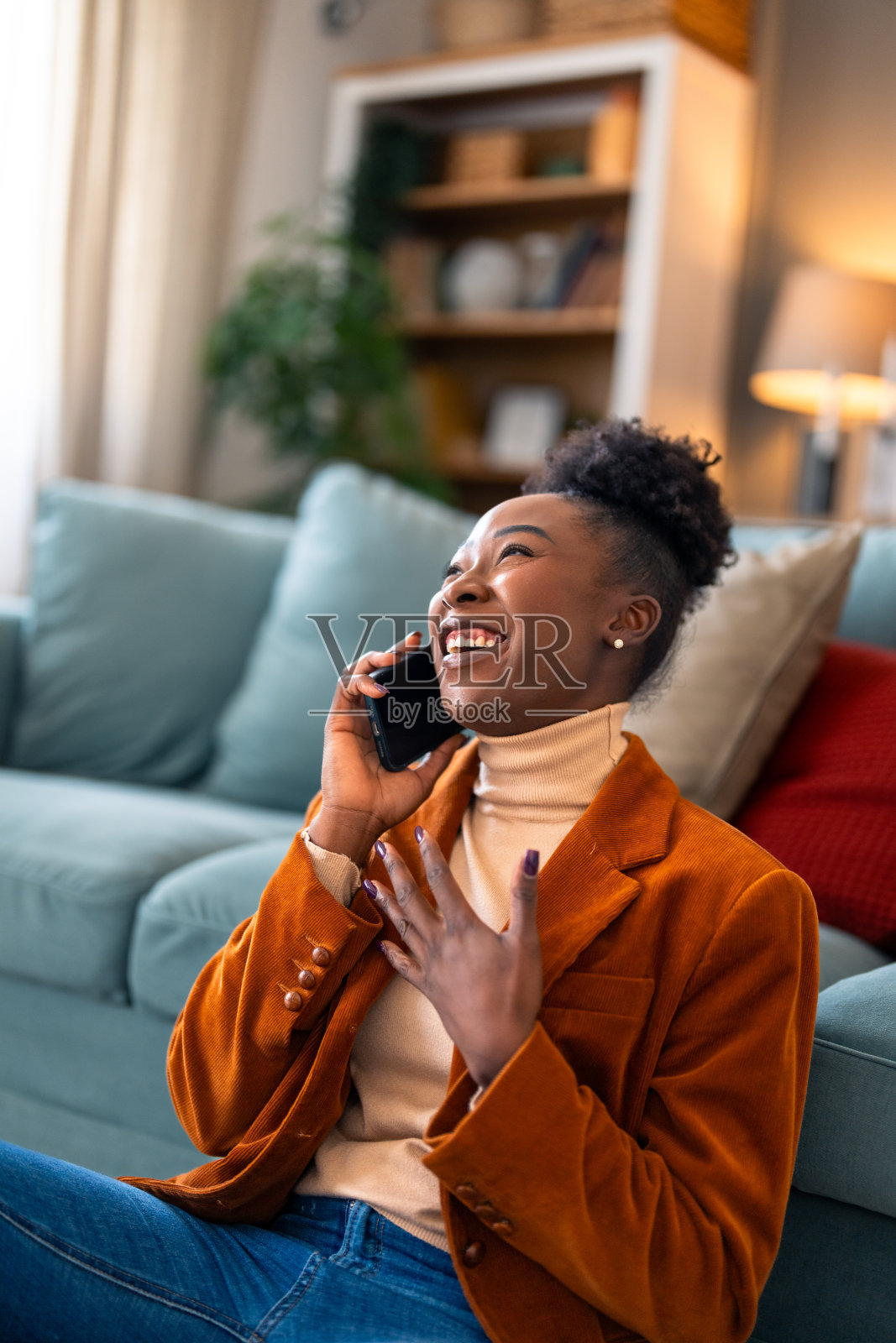 年轻的非洲妇女在一个非常有趣的电话交谈中大笑照片摄影图片