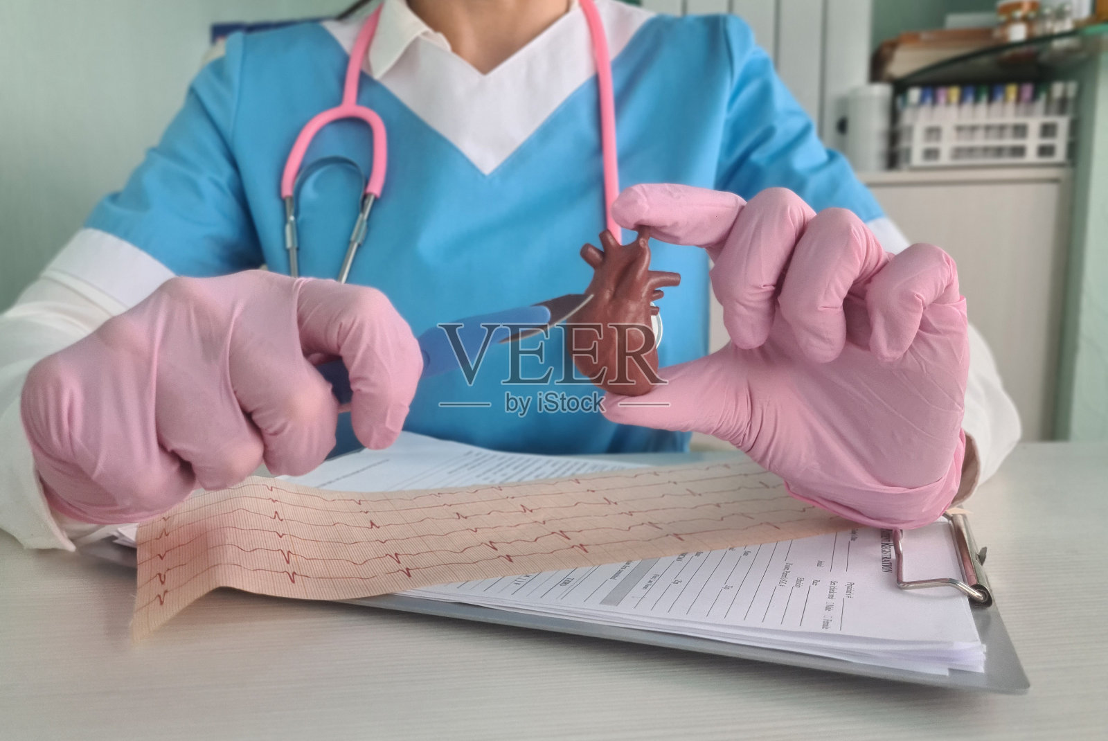 医生拿着手术刀和心电图条的心脏模型照片摄影图片