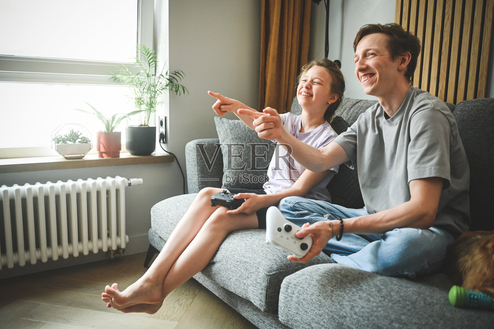 哥哥和妹妹坐在沙发上玩电子游戏照片摄影图片