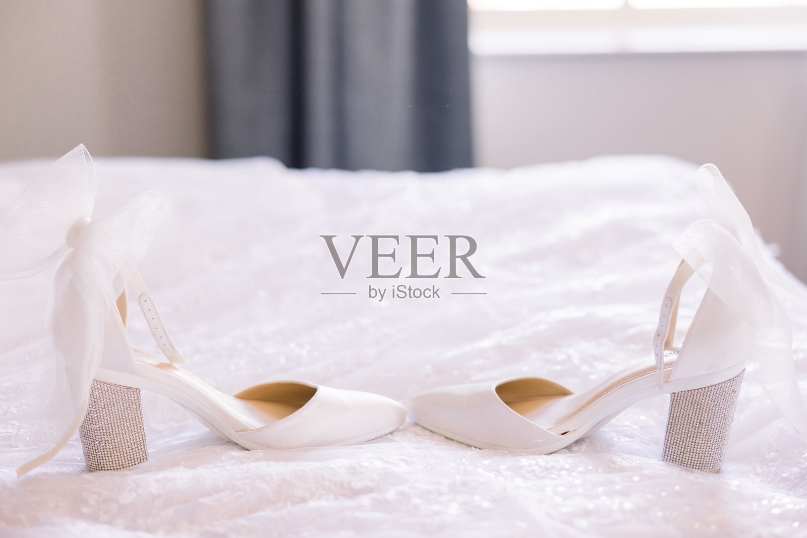 婚礼白色的高跟鞋在白色的床上面对面。照片摄影图片