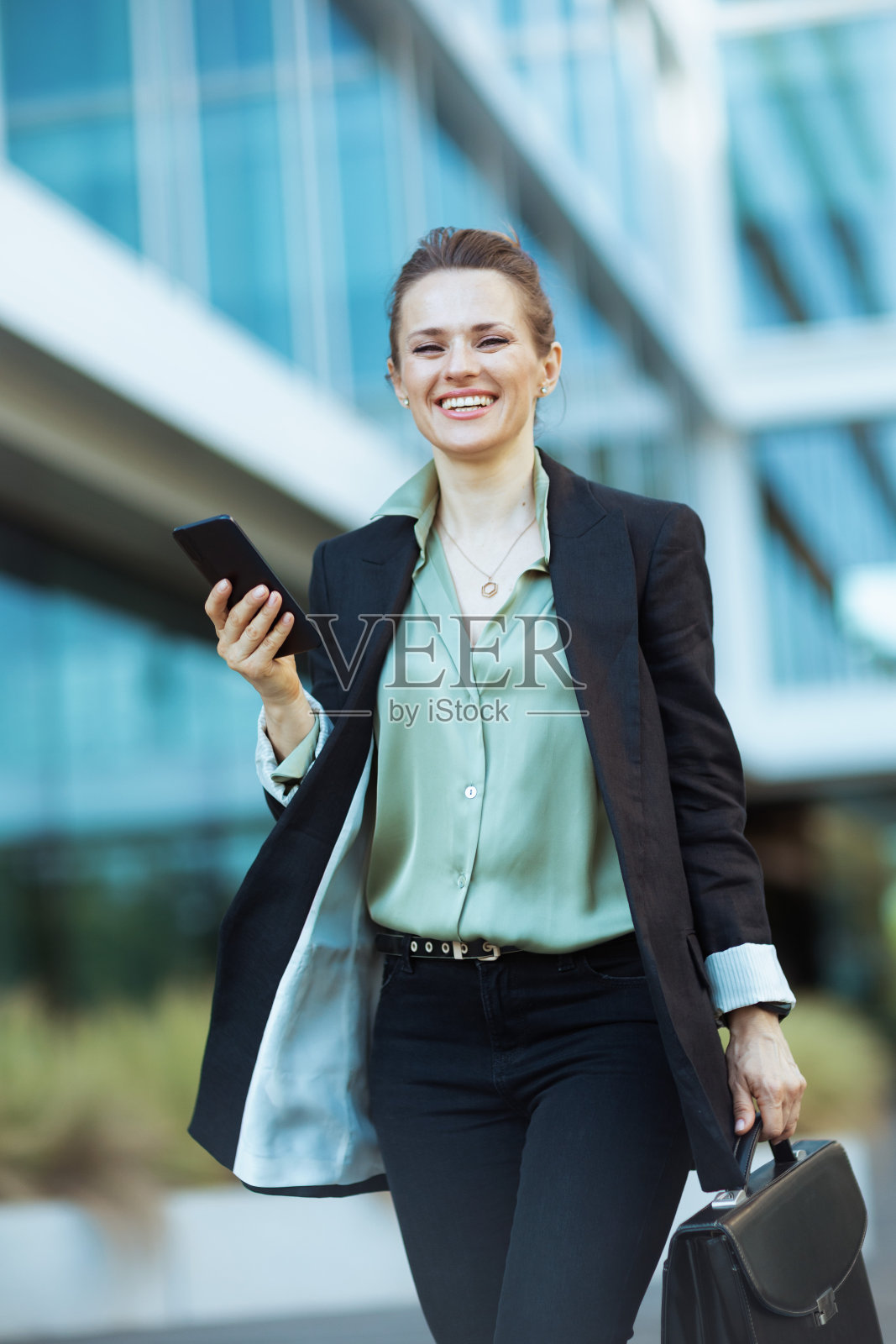 微笑的女员工在商务中心附近散步照片摄影图片