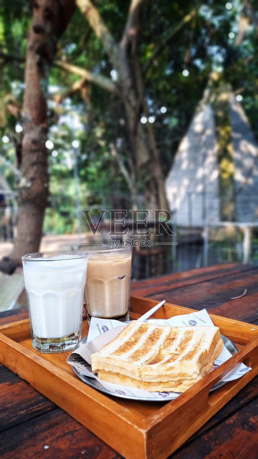 咖啡、牛奶和烤面包放在可以看到自然景观的桌子上照片摄影图片
