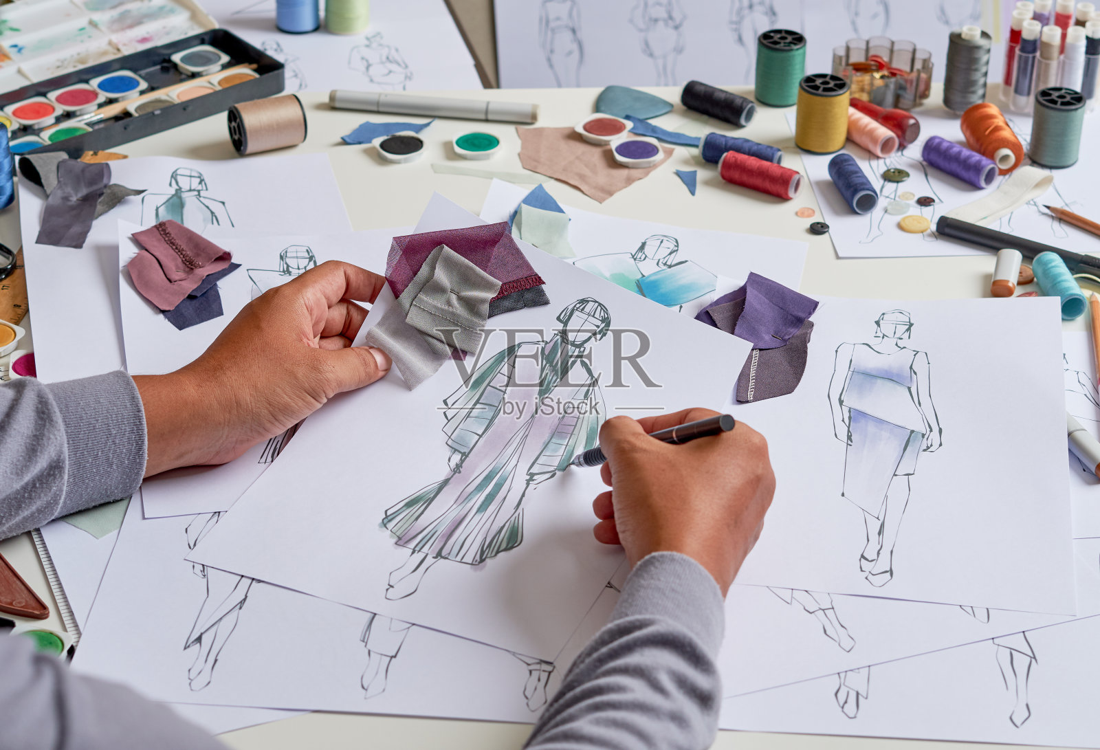 时装设计师的时尚图纸草图纺织面料服装。设计师创意工坊工作室。照片摄影图片