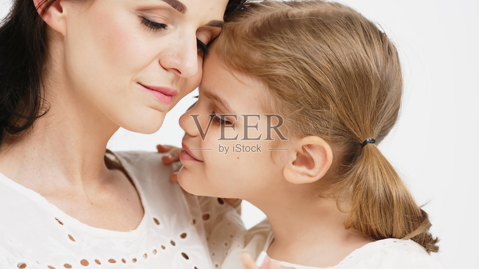 在浅色背景下,一对感人而温柔的母女的特写。妈妈温柔的抚摸。家庭的概念。照片摄影图片