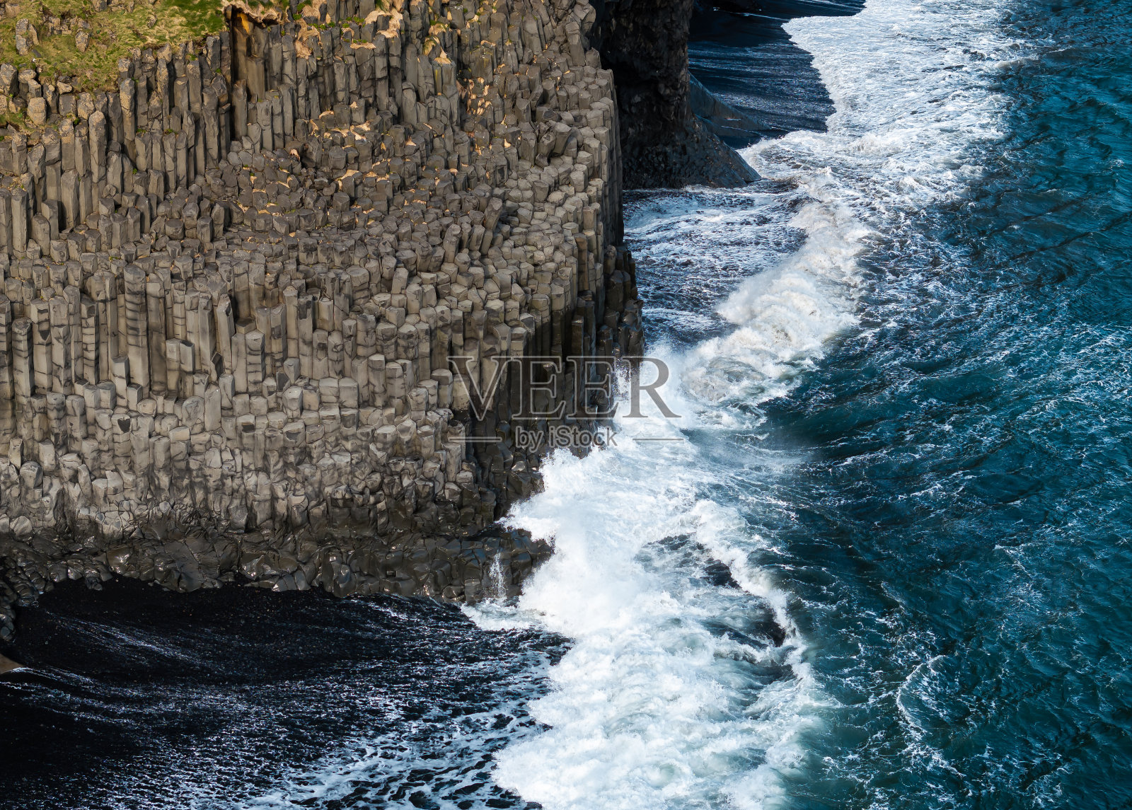 鸟瞰图:冰岛Reynisfjara黑沙滩上的玄武岩柱和海浪。照片摄影图片