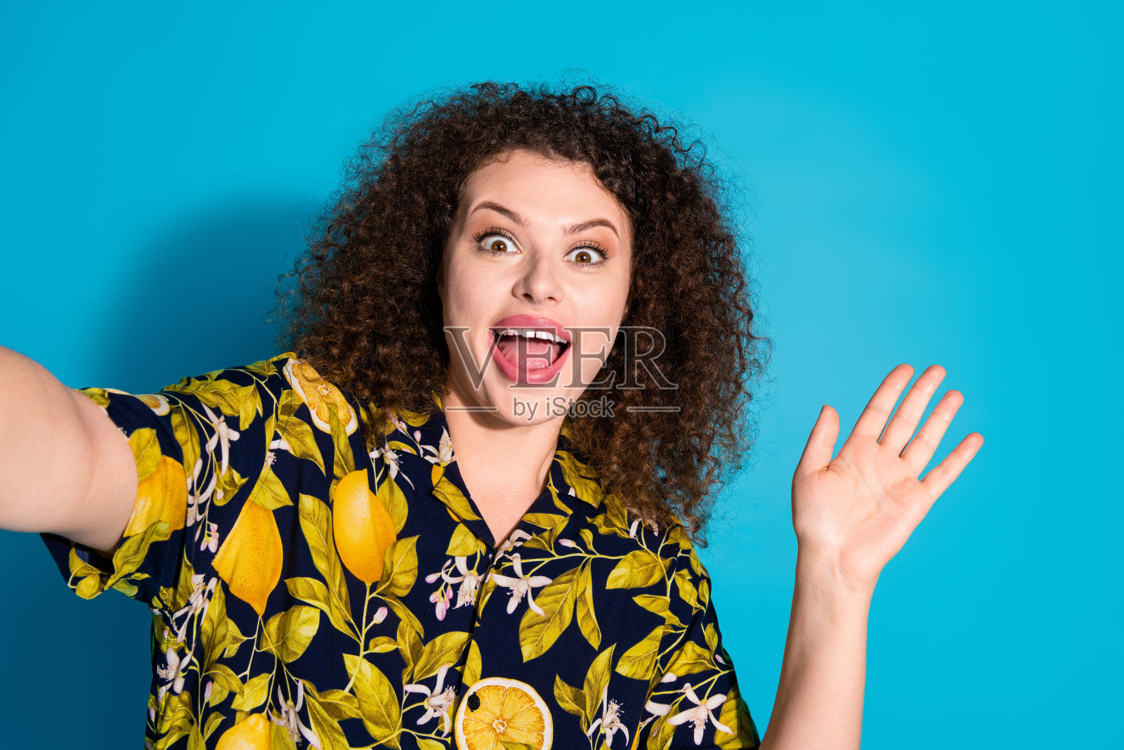 照片中可爱可爱的女孩穿着印花衬衫录制视频,挥舞着手臂hi空空间孤立的蓝色背景照片摄影图片