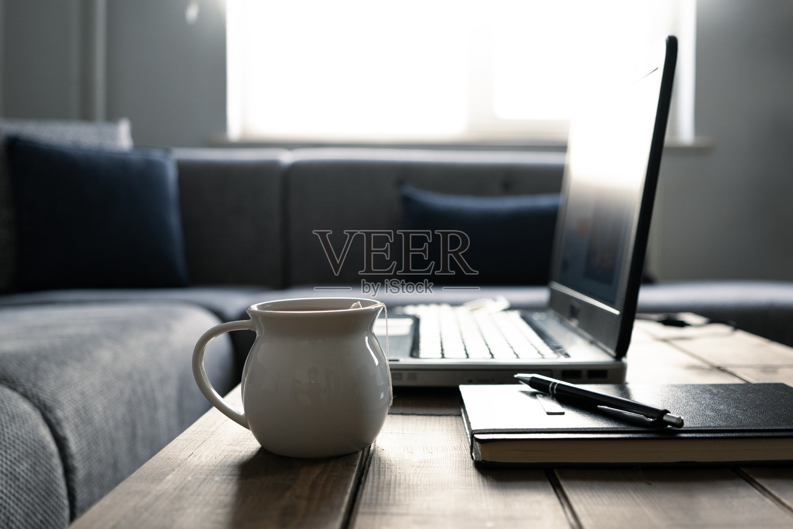 手提电脑、笔记本和茶几上的茶杯照片摄影图片
