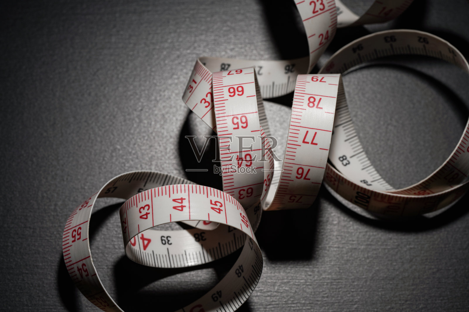 白色卷尺被隔离在黑暗的背景上照片摄影图片