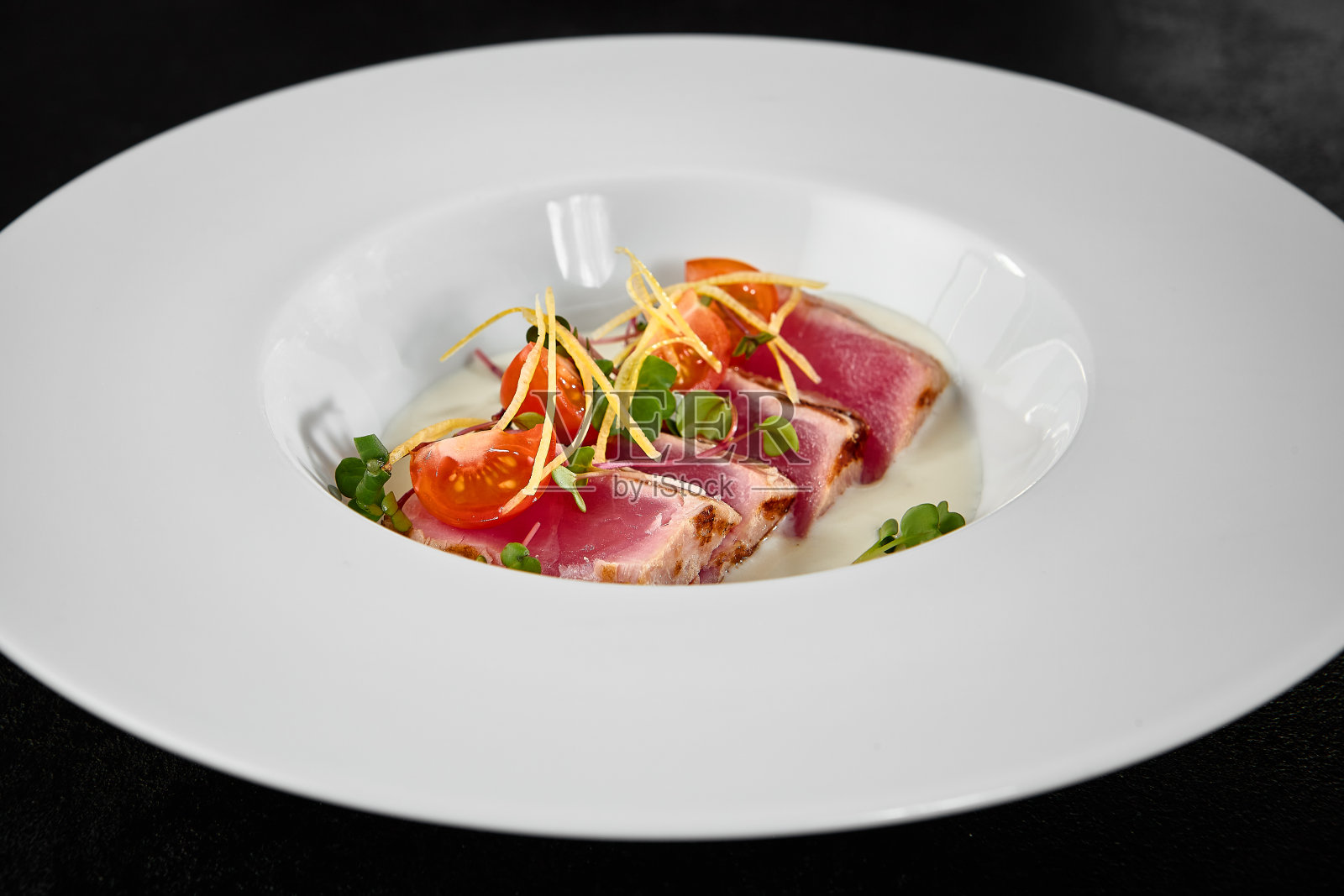 新鲜的金枪鱼泷木,优雅的白色盘子,配以圣女果和青菜照片摄影图片