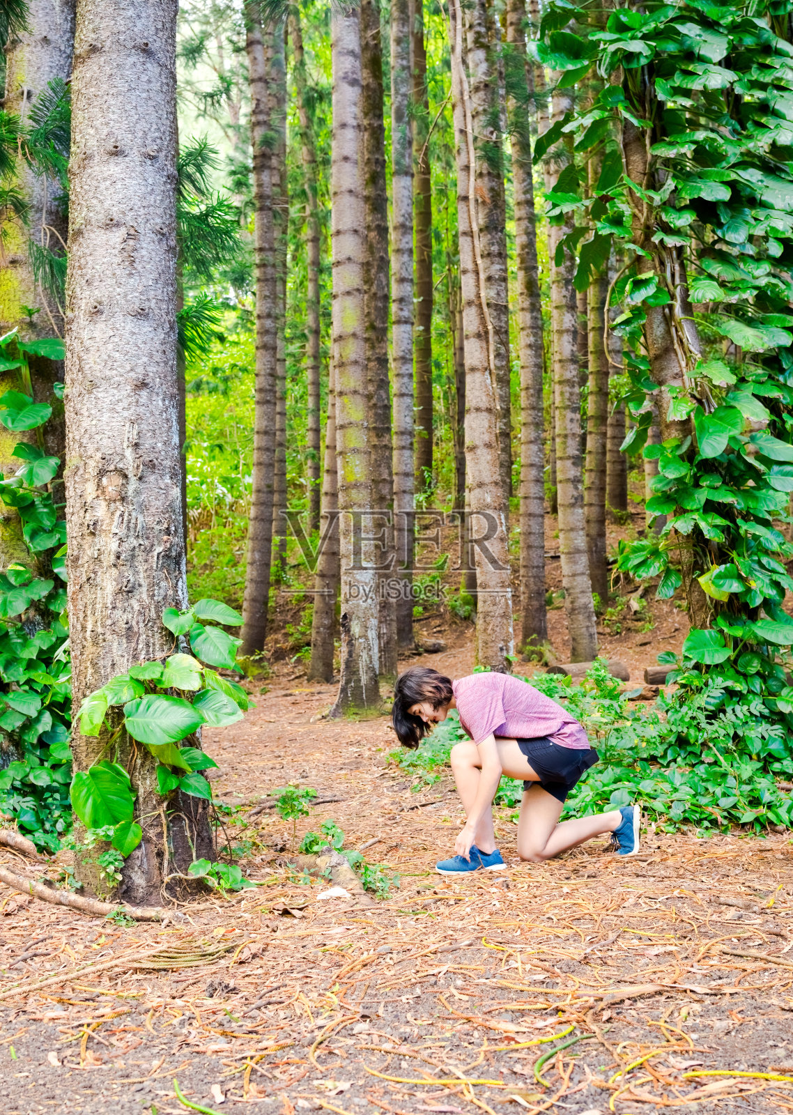 十几岁的女孩在穿过森林小径前系鞋带照片摄影图片