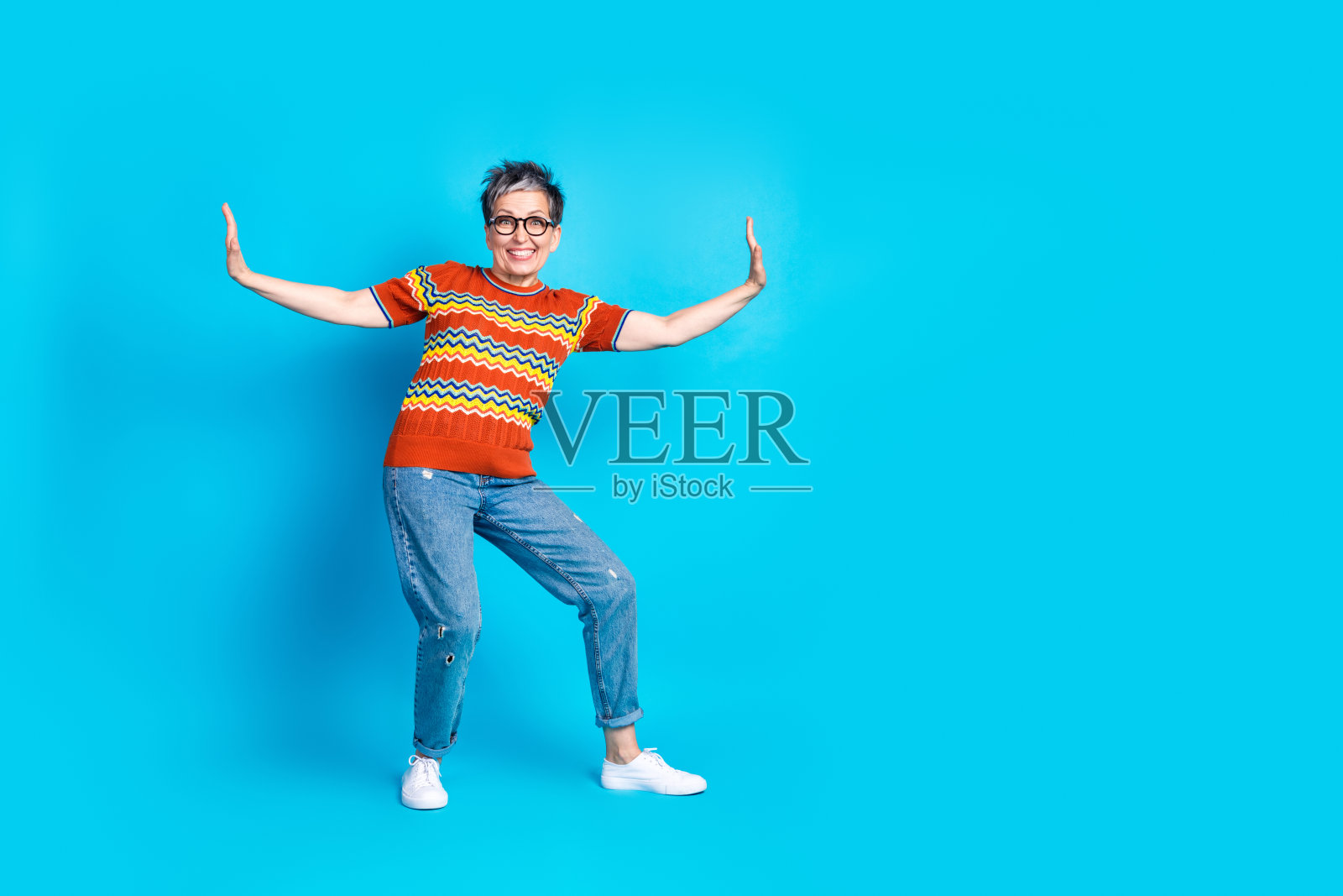 漂亮的老年妇女跳舞的全尺寸照片,在蓝色背景上穿着t恤照片摄影图片