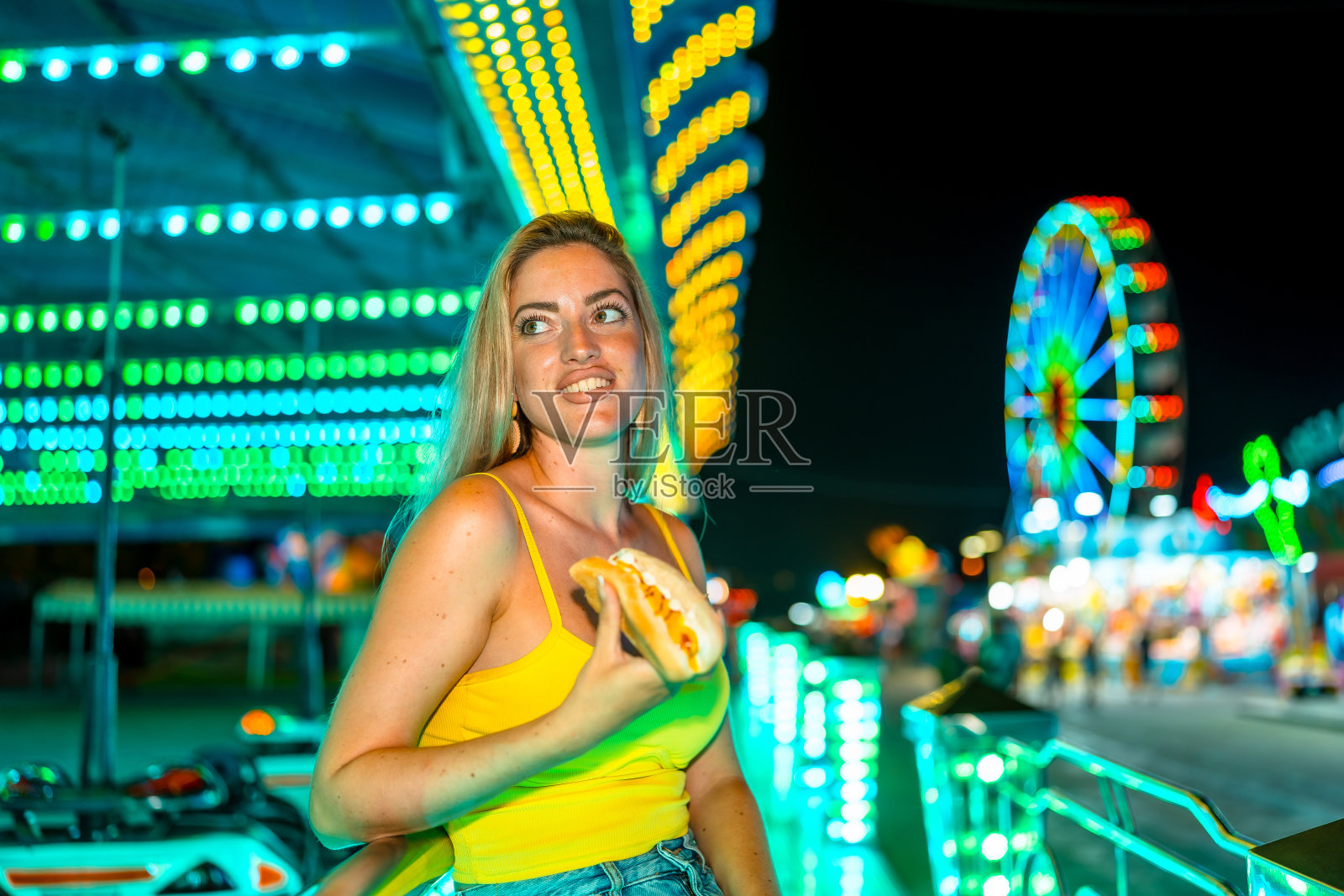 在夜市上拿着不健康热狗的女人照片摄影图片