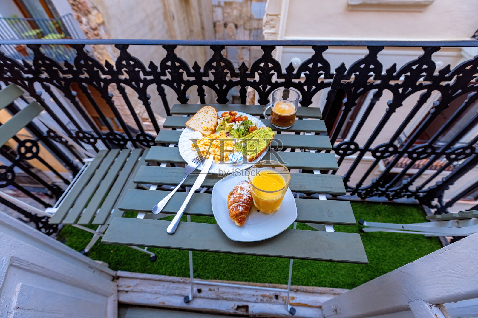 在西班牙老城的阳台上,早餐有炒鸡蛋、咖啡、橙汁和鳄梨吐司照片摄影图片