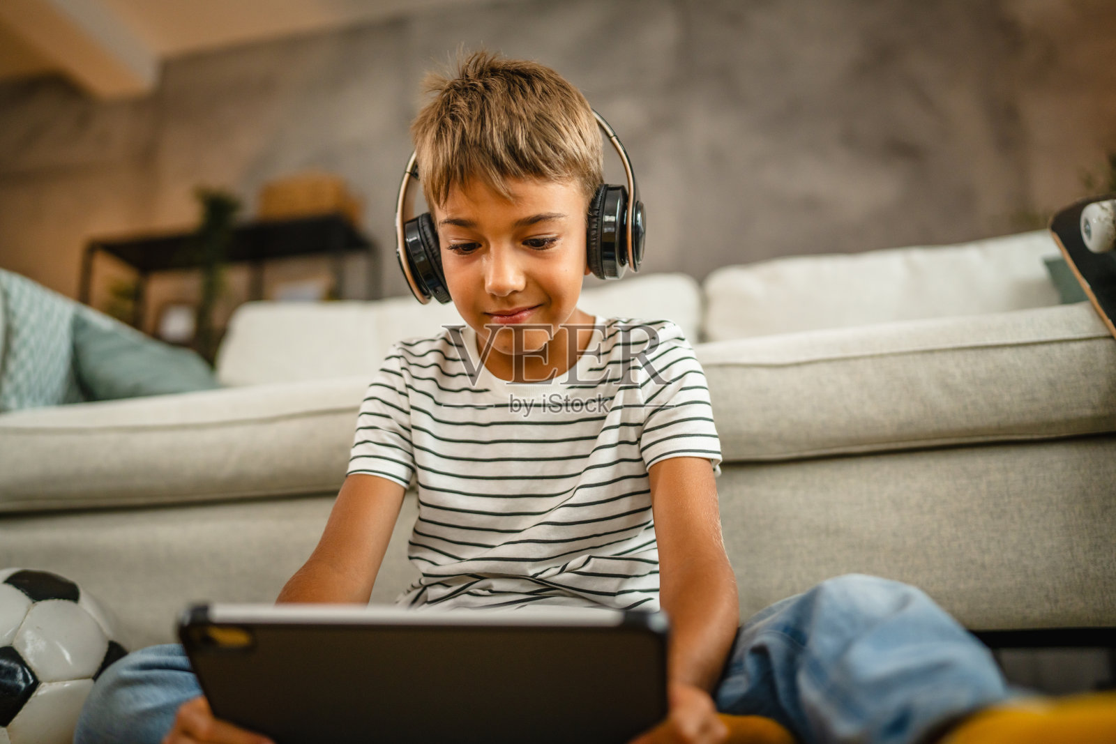 戴着耳机的小男孩坐在地板上使用数码平板电脑照片摄影图片